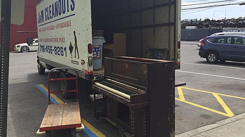 Unwanted piano being loaded on a hauling truck in New York City